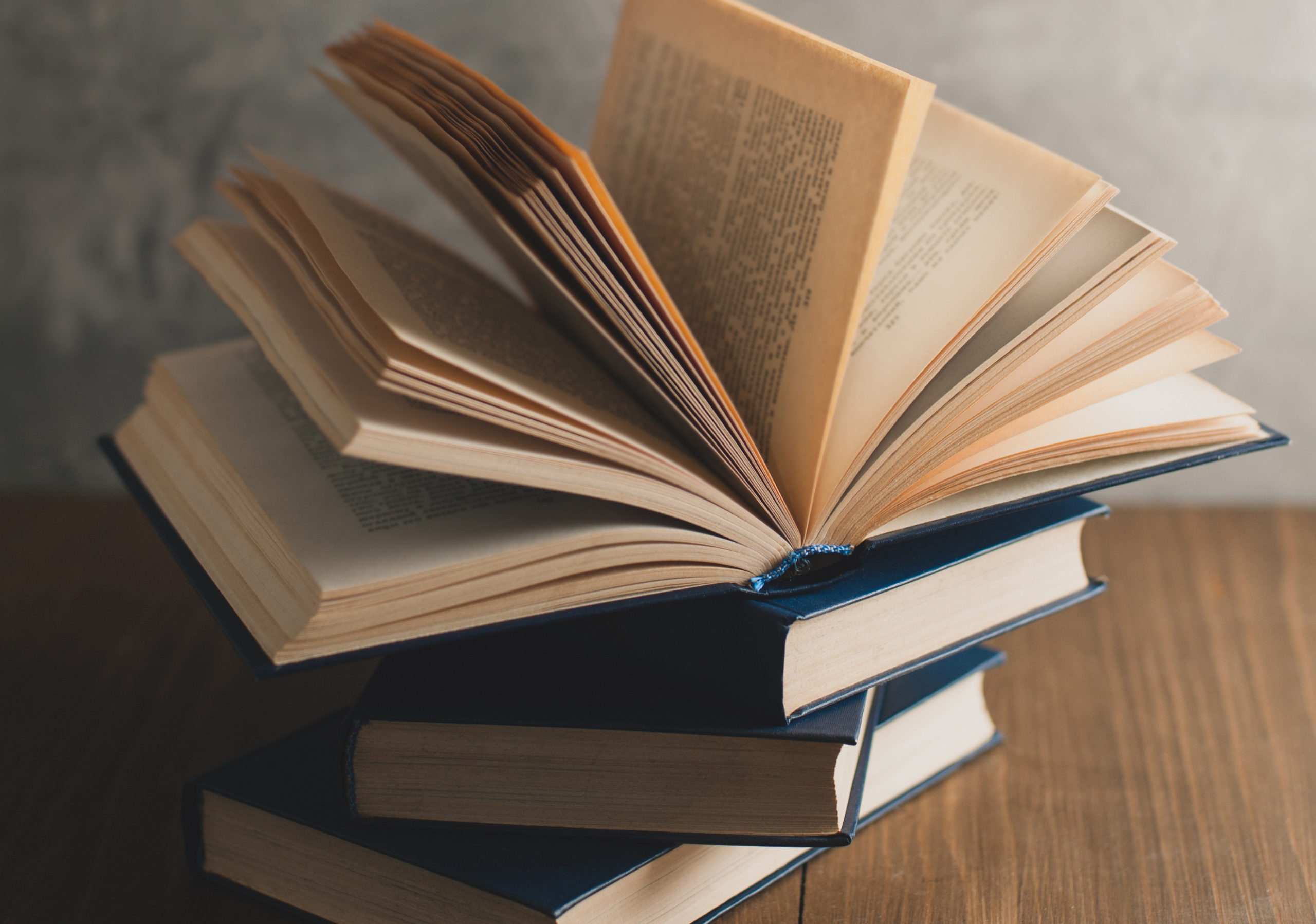 stack of books on a wooden table and on gray concrete wall background